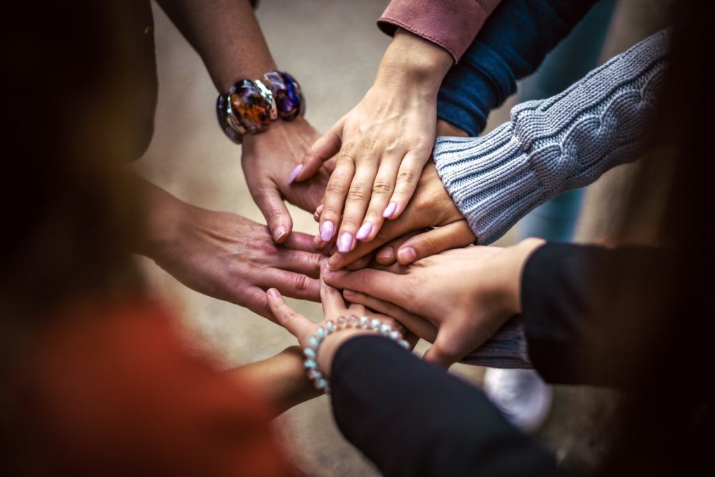 Mains de plusieurs personnes assemblées, symbole d'un nouveau départ avec un coach professionnel.