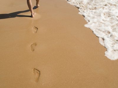 Personne marchant dans le sable, symbole d'une approche réflexive.