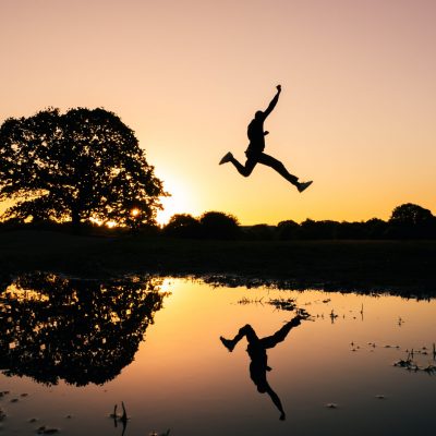 Personne sautant par-dessus une rivière, osant sauter le pas pour avancer professionnellement.